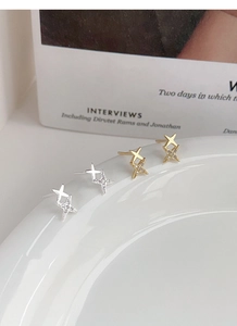 Detail of S999 silver four-pointed star earrings in gold and silver finishes with zircons