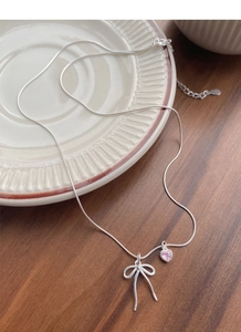 S925 silver bow necklace with pink heart pendant displayed on a ceramic plate