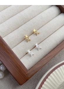 Close-up of gold and silver S999 silver star stud earrings with zircon inlay in a wood box