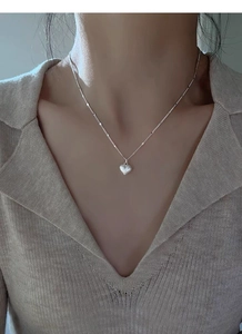 Close-up of S925 sterling silver heart necklace with brushed texture on female model