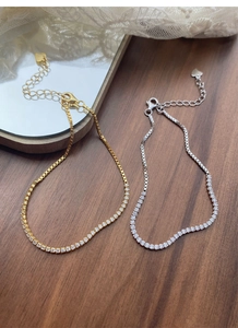 Detail of silver and gold tennis bracelets with crystal heart charms on wooden background