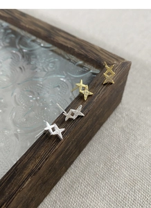 Detailed macro view of S999 silver star stud earrings with cubic zirconia on wood
