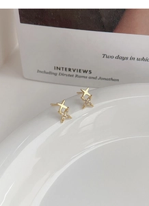 Close-up of gold S999 silver star stud earrings with zirconia stones on a ceramic plate
