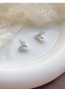 Detail shot of elegant S925 silver bow earrings with shiny pearls and zircons