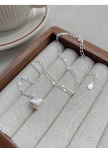Macro detail of S925 sterling silver heart necklace with frosted texture on wood box