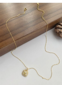 Detail of a square gold pendant necklace with a yellow gemstone and sparkling micro-diamonds