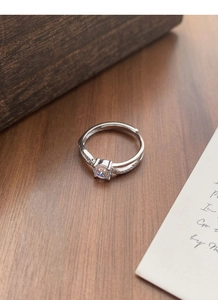 Macro detail of S925 sterling silver ring with four-prong zircon and woven diamond band