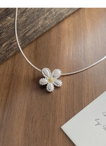 Detail view of a two-tone silver daisy pendant necklace with a golden center and beaded edges