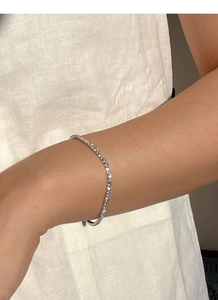Detail shot of a slender S925 silver tennis bracelet with glittering round-cut crystals