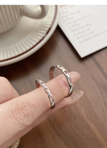 Close-up of interlocking S925 silver rings with pavé zircon detail on a wooden table
