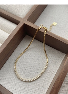 Detail of gold tennis bracelet with cubic zirconia and heart charm in wooden box