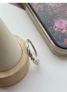 Close-up of S925 sterling silver Mobius ring on a wooden cone stand with soft lighting