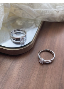 Close-up of S925 sterling silver couple rings with moissanite accents on a wooden desk