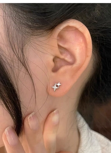 Detail of S999 sterling silver four-point star stud earrings worn by a model on the ear lobe