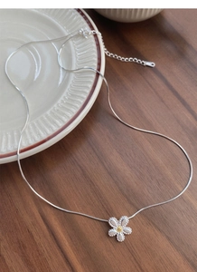Detail of S925 sterling silver daisy pendant with golden center on a snake chain