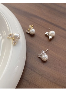 Detailed view of silver and gold bow-shaped pearl earrings with sparkling zirconia