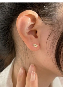 Detailed view of S999 silver four-pointed star stud earrings with cubic zirconia on ear