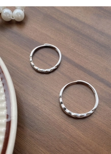 Detailed view of S925 silver Mobius rings with woven texture and faceted design on wood