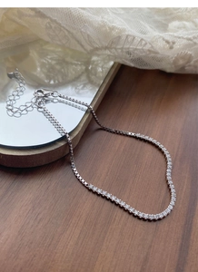 Detail of S925 sterling silver tennis bracelet with cubic zirconia on a wooden surface