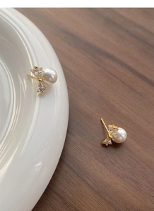 Detail of S925 silver bow stud earrings with white pearl and sparkling zircon accents