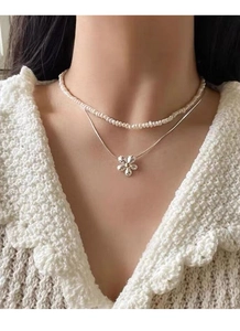 Detail showing a double-layered S925 silver necklace with pearls and a crystal flower pendant