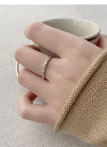 Elegant twisted silver S925 Mobius ring with sparkling zircons worn in a cozy cafe setting
