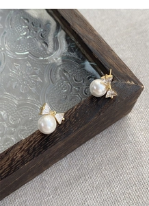 Close-up of S925 silver bow stud earrings with white pearl and sparkling zircon accents