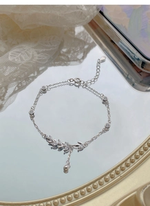 Macro shot of S925 silver wheat ear bracelet with cubic zirconia on reflective surface