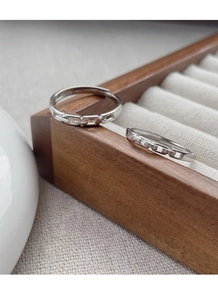 Close-up of S925 sterling silver interlocking rings on a wooden display tray