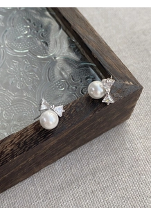 Detailed close-up of S925 silver bow stud earrings with white pearls and zircons