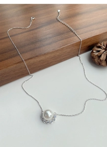 Detail of silver necklace with large white pearl and crescent cubic zirconia stones