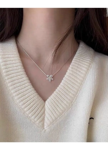 Close-up of S925 sterling silver daisy pendant on snake chain worn on a model