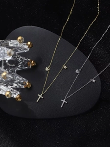Detailansicht von Kreuzketten in Gold und Silber mit Herz- und Sternanhängern auf Display