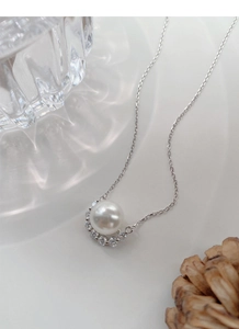 Close-up of S925 silver necklace with white round pearl and zircon curved inlay