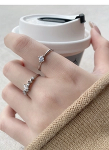 Close-up of S925 silver butterfly and zircon rings held with a coffee cup