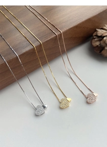 Détail de pendentifs cœur en argent, or et or rose avec sertissage de pierres