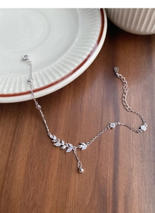 Detail of adjustable S925 silver leaf bracelet with sparkling cubic zirconia on wood table