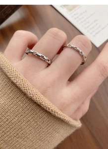Macro view of interlocking silver chain rings with pavé cubic zirconia on fingers