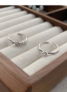 Detailed macro view of S925 sterling silver butterfly and solitaire rings on velvet padding