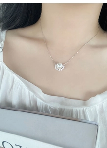 Close-up of S925 silver necklace with white pearl and sparkling zircon pendant on neck