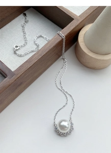 Detail of S925 silver necklace with round pearl pendant and sparkling cubic zirconia stones