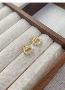 Détail de boucles d'oreilles perles roses vintage sur une boîte à bijoux beige
