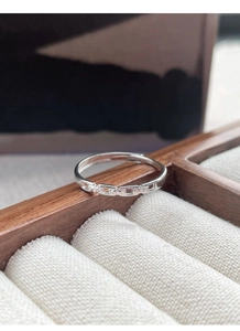 Macro shot of silver chain link ring with tiny zircons on a textured jewelry box liner