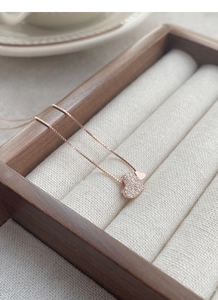 Vue macro du collier cœur en or rose avec zircons sertis et chaîne box raffinée