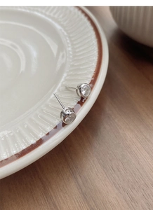 Macro shot of minimalist S925 silver stud earrings with zircon on a ceramic plate