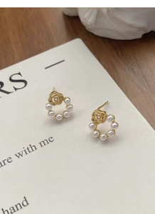 Gros plan de boucles d'oreilles roses dorées avec perles sur fond décoratif et esthétique