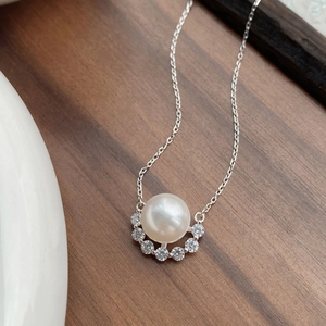 Elegant S925 sterling silver necklace featuring a round pearl and cubic zirconia on wood