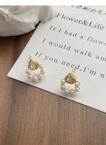Détail de boucles d'oreilles rose vintage dorée avec un cercle de perles blanches