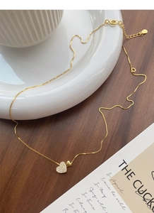 Détail macro d'un collier pendentif coeur doré orné de zircons blancs étincelants