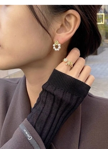 Détail de boucles d'oreilles rose dorée et perle avec bague florale assortie élégante